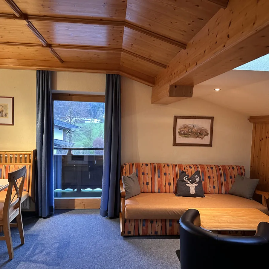 Wohnbereich mit Sofa, Tisch und Fenster zum Außenbereich