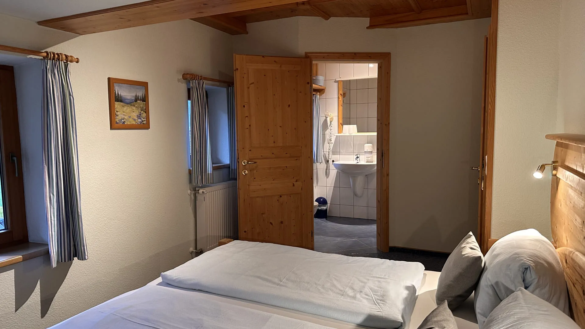 Helles Schlafzimmer mit zwei Betten und Blick auf das Bad.