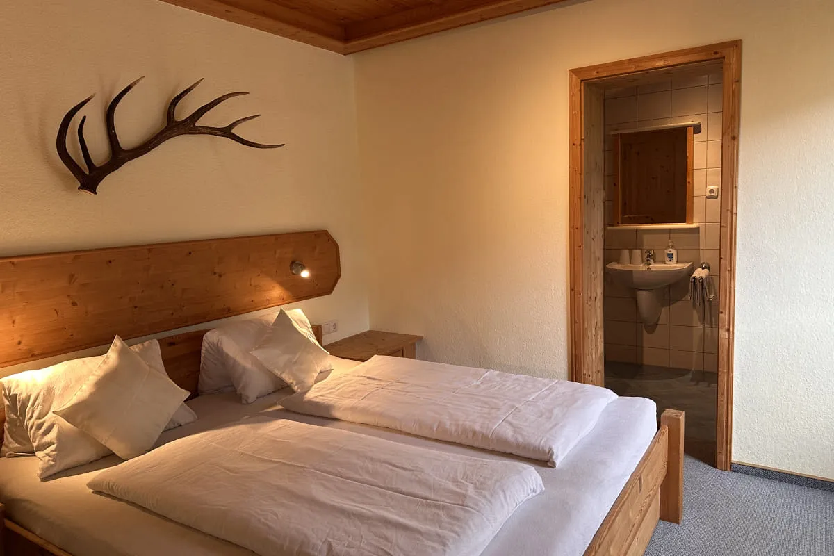 Helles Schlafzimmer mit Holzdekor und eigener Badezimmertür
